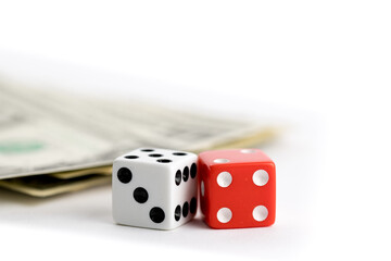 extreme close up of a pair of red and a white dice and a stack of US dollar paper currency isolated on white