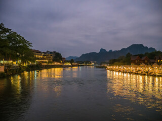 Obraz premium Beautiful view of nam song river with riverside restaurant and the mountain in the night at Vangvieng city Lao.Vangvieng City The famous holiday destination town in Lao.
