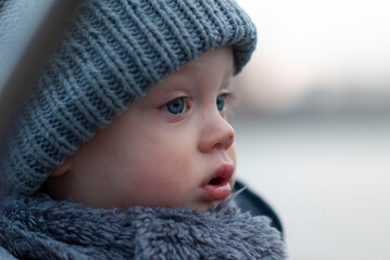Portrait of a pensive child in a hat and scarf close-up with a tear in his eyes