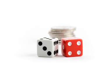 extreme close up of a pair of red and a white dice and a stack of silver coins isolated on white