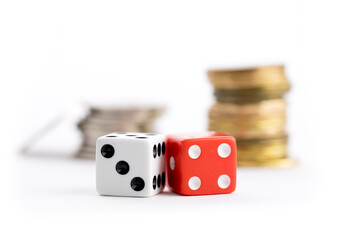 extreme close up of a pair of red and a white dice and a stack of silver and gold coins isolated on white