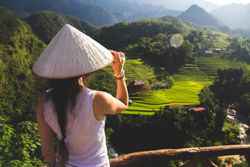 a young European lady dons a traditional Vietnamese hat, immersing herself in the rich cultural...