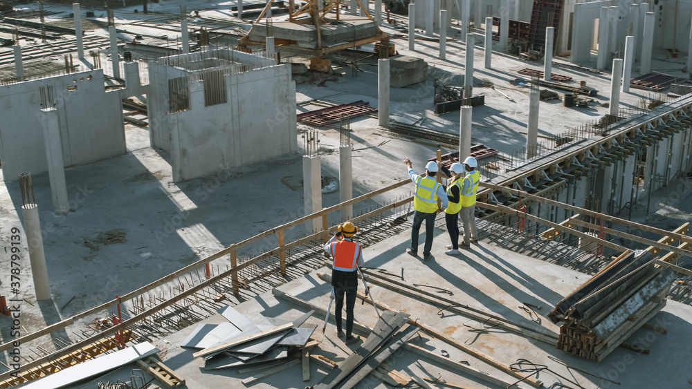 Wall mural aerial shot of a new constructions development site with diverse team of engineers and architects di