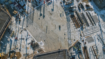 Aerial Shot of a New Constructions Development Site with High Tower Cranes Building Real Estate. Heavy Machinery and Construction Workers are Employed. Top Down View.