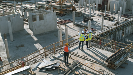 Aerial Shot of a New Constructions Development Site with Diverse team of Engineers and Architects Discussing Real Estate Projects. Heavy Machinery and Construction Workers are Working in the Area.