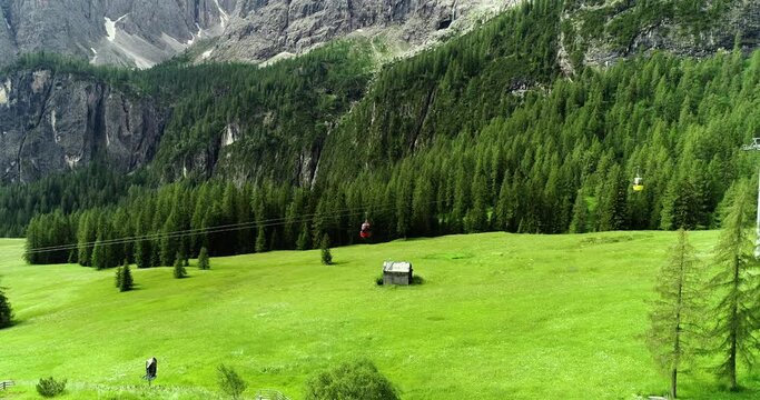 Cable car in valley in summer. It is surrounded by green pine tree forest and mountains under the sunlight - aerial view with a drone 4K
