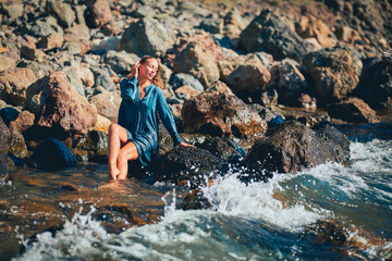 Beautiful female sitting on stone. Crystal clean sea water. Summer time relax. Meditation and relax concept, copy space.