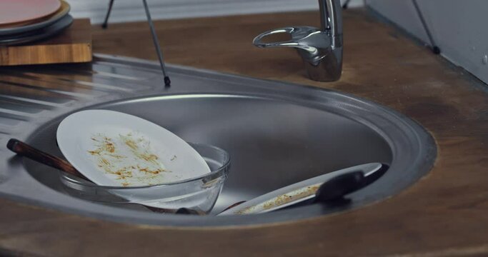 Cropped view of man putting tableware in kitchen sink 