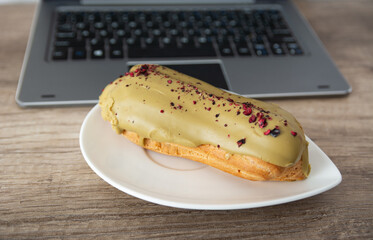 Fresh sweet eclair on office table.