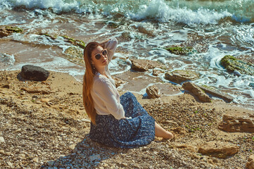 Young beautiful woman in a white blouse resting on the sea coast