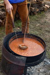 A man cooking up some stew at an autumn reenactors festival.
