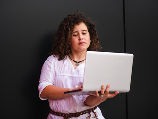 A Caucasian woman with curly hair holding a laptop