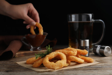 Pile of delicious crunchy fried onion rings and rosemary on wooden table