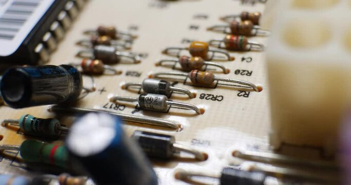 Many resistors, capacitors and electronic components on an old retro circuit board controller.