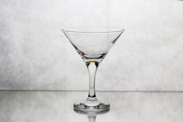 In a Martini glass, standing on a white background, the drink is poured from above