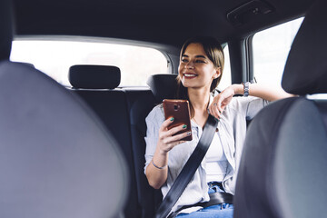 Smiling young woman with smartphone in car