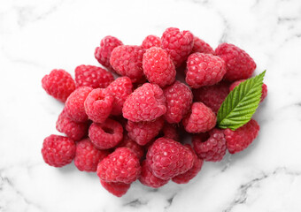Delicious fresh ripe raspberries with green leaf on white marble table, above view