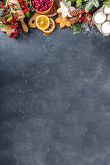 Ingredients for Christmas cooking, winter baking cookies, gingerbread, fruitcake, seasonal drinks. Cranberries, dried oranges, cinnamon, spices, flour on dark stone table, copy space top view