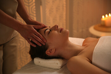 Obraz na płótnie Canvas Young woman receiving head massage in spa salon