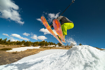 woman skier athlete makes a jump in flight on a snowy slope against the backdrop of a blue sky of...