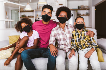 African American parents and cute small kids wearing protective masks at home. Stop the virus and...