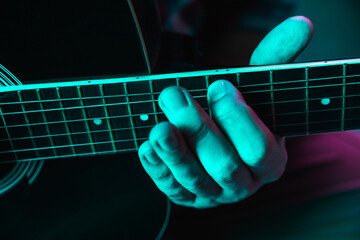 Close up of guitarist hand playing guitar, macro. Concept of advertising, hobby, music, festival, entertainment. Person improvising inspired. Copyspace to insert image or text. Colorful neon lighted.