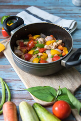 Vertical view of saute vegetables and boiled chicken in a black pan