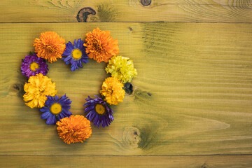 Image of heart shape made with  beautiful flowers on wooden background. 