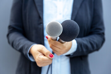 Television journalist holding microphone during media interview. Journalism concept.