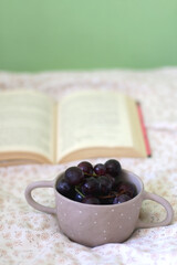 Bowl of grapes and open book on a bed. Selective focus.