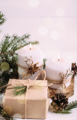Christmas candles, gift and fir branches on a white wooden background with lights. greeting card with copy space