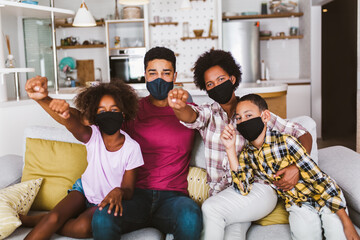 African American parents and cute small kids wearing protective masks at home. Stop the virus and epidemic diseases.