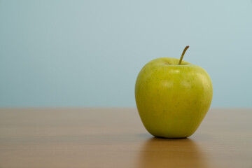 Fresh green apple on a table on the blue background