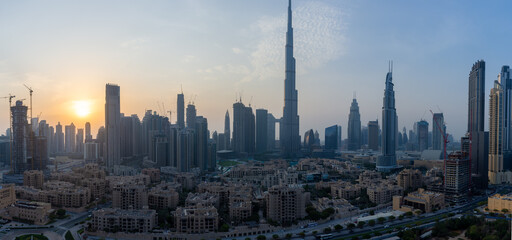 Fototapeta na wymiar Iconic panorama at sunset of Burj Khalifa and Dubai Skyline as sun sets with and other skyscrapers in the Middle East with blue sky
