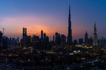 Iconic panorama at sunset of Burj Khalifa and Dubai Skyline as sun sets with blue and purple colors and other skyscrapers in the Middle East "