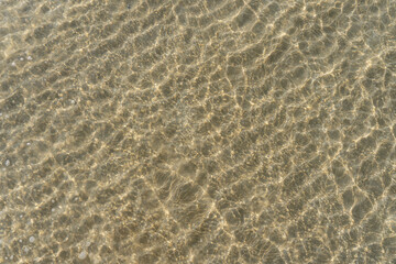 Fototapeta na wymiar Aerial top view of clear water and patterned sand as the tide comes in at the beach.