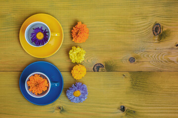 Beautiful flower petals in a cups  on wooden background.