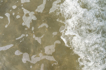 Aerial top view of white waves and water tide coming in at the beach.