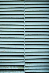 Closeup of a metal ventilation grill on the street. Old rusty ventilation grill in front of an industrial building. The grille is painted turquoise.