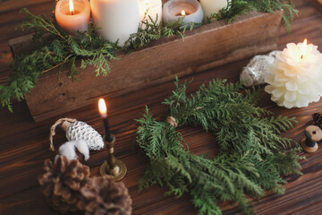 Obraz na płótnie Canvas Rustic christmas wreath with candles, pine cones, thread and ornaments on wooden table.