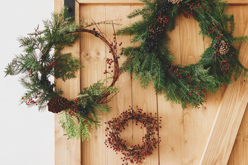 Creative natural and different christmas wreaths hanging on stylish rural door