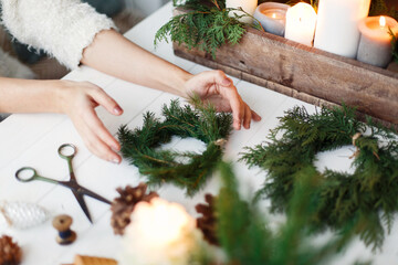 Florist hands making simple stylish christmas wreath with fir branches