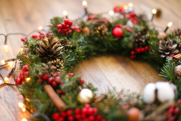 Fototapeta na wymiar Christmas wreath decorations close up on rustic wood in lights.