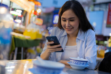 Traveler women  using smartphone in chinatown at night time.