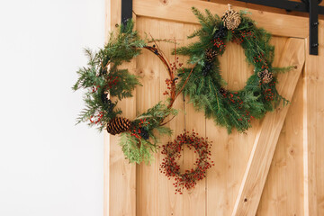 Rustic christmas wreaths on wooden door indoors, festive holiday decoration