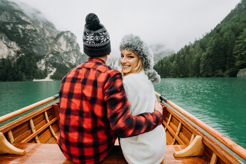Romantic couple on a boat visiting an alpine lake at Braies Italy. Tourist in love spending loving...