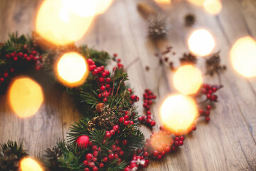 Christmas wreath decorations close up on rustic wood in lights.