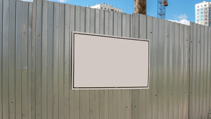empty information board with mockup on steel fence of construction site