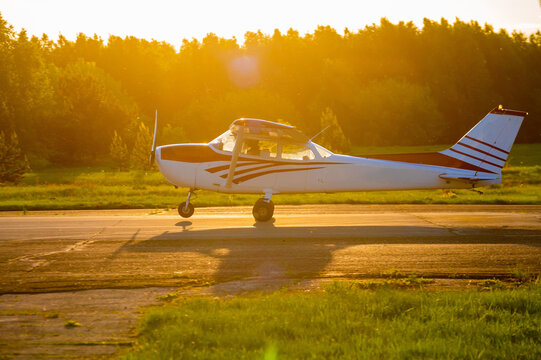 Landed small four-seater airplane at sunset background.