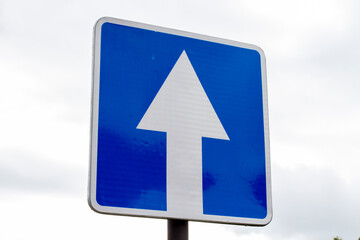 One way road sign on cloudy sky background, close-up.